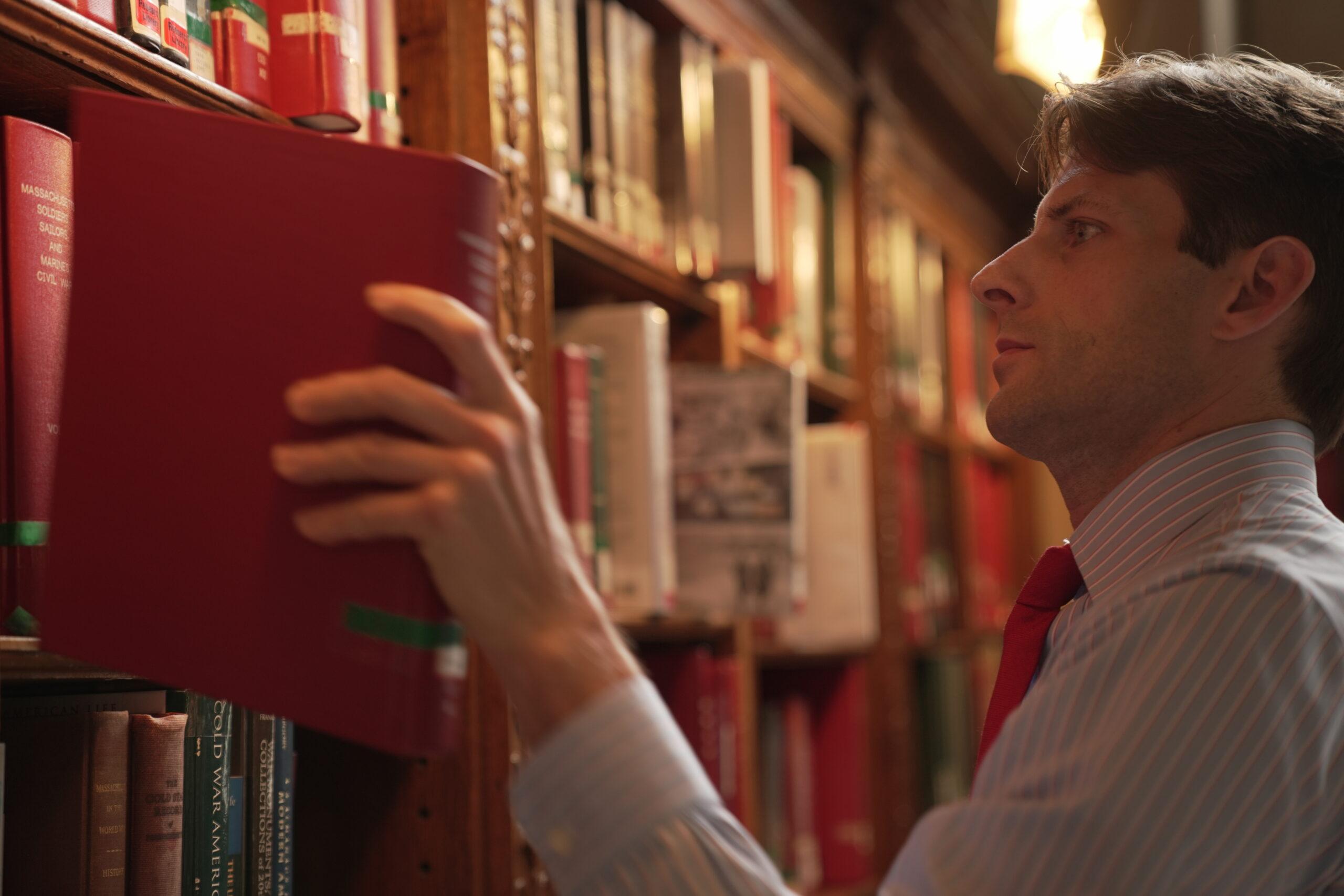 Attorney Finn Gavagan pulling book from shelf researching
