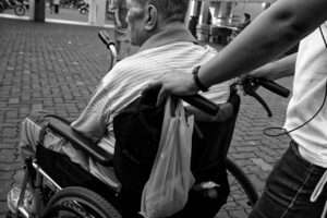 Elderly man being pushed in wheelchair